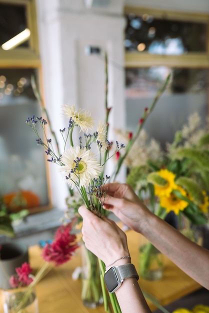 La donna del fiorista fa un mazzo di fiori di campo freschi