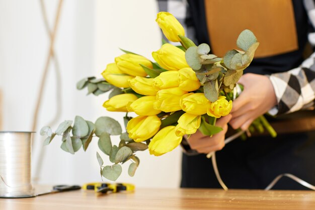 La donna del fiorista fa un mazzo di tulipani gialli freschi. Studio di disegno floreale