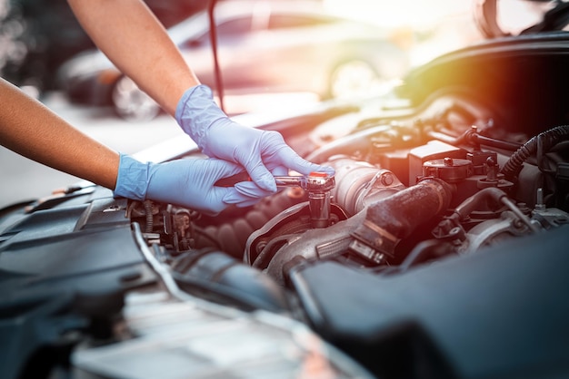 La donna del meccanico dell'automobile lavora nel garage con un'automobile rotta Servizi di riparazione primo piano delle mani di una donna che riparano un'automobile