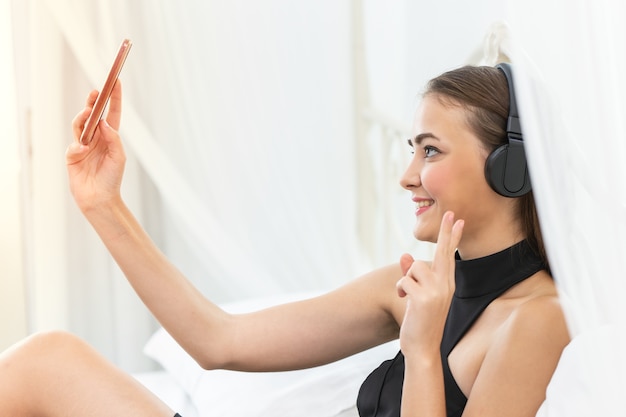 la donna del primo piano che usando lo smartphone ascolta la musica per godere del suo selfie della macchina fotografica di stile di vita