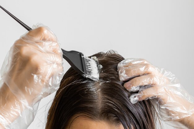 La donna del primo piano passa la tintura dei capelli facendo uso di una spazzola nera. Colorazione di capelli bianchi a casa.