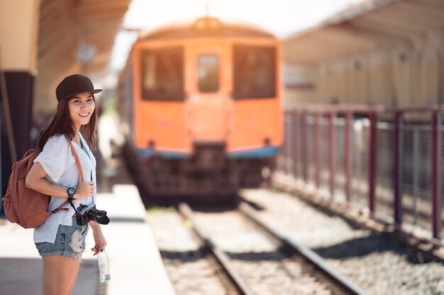 La donna del viaggiatore che cammina e aspetta il treno sulla piattaforma ferroviaria Colore d&#39;annata