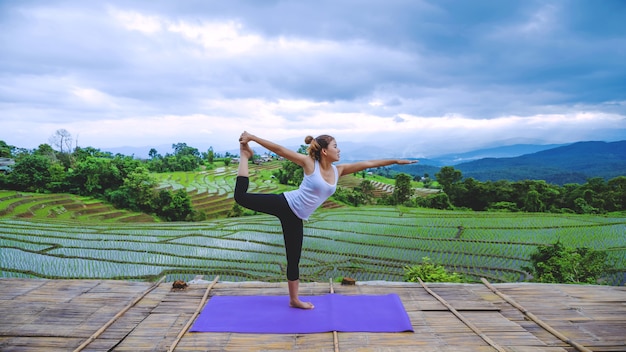 La donna del viaggiatore della libertà si rilassa durante le vacanze. Gioca se yoga Stand paesaggi naturali sulle montagne e Field Rice.