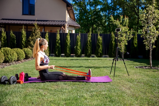 La donna dell'allenatore di fitness crea un video blog per telefono sull'allenamento e sull'uso della gomma da palestra