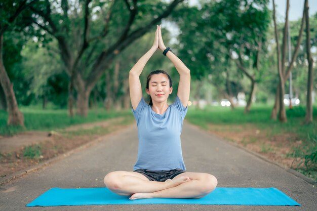 La donna dell'Asia pratica lo yoga e medita al parco. Stile di vita sano e concetto di Yoga.