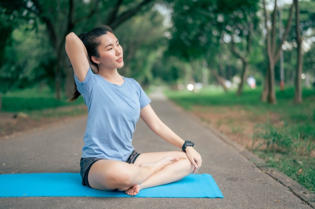 La donna dell'Asia pratica lo yoga e medita al parco. Stile di vita sano e concetto di Yoga.