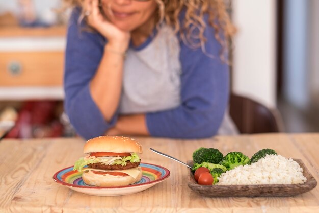 La donna deve scegliere tra hamburger o verdure e alzarsi per avere uno stile di vita sano e ottimo e per essere felice con se stessa - l'uomo seleziona quale tipo di cibo preferisce