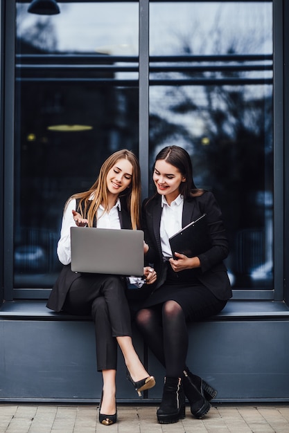 La donna di affari che parla per il business plan mentre si siede sul computer portatile! Vicino al centro uffici!