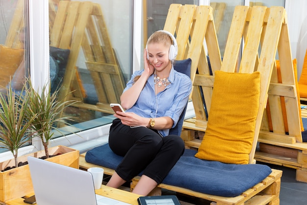 La donna di affari graziosa sta ascoltando musica in sottotetto moderno. Lavoro freelance, relax e concetto di svago. Donna in affari. Le free lance nel centro di coworking stanno riposando.