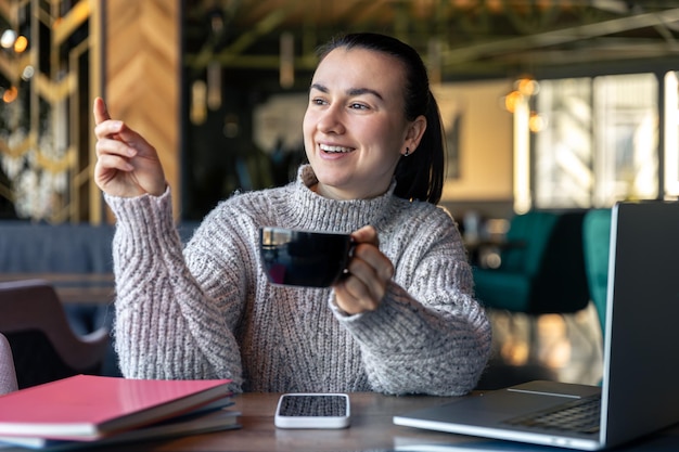 La donna di affari in un caffè con un computer portatile beve il tè