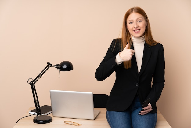 La donna di affari in un ufficio che dà i pollici aumenta il gesto