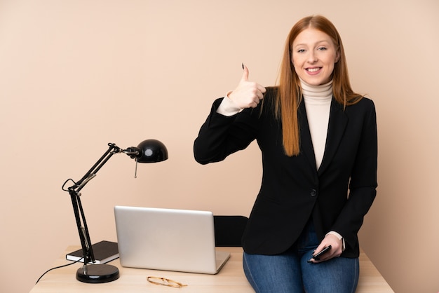La donna di affari in un ufficio che dà i pollici aumenta il gesto
