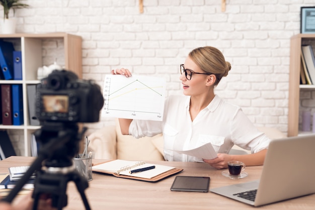 La donna di affari mostra i grafici alla macchina fotografica.