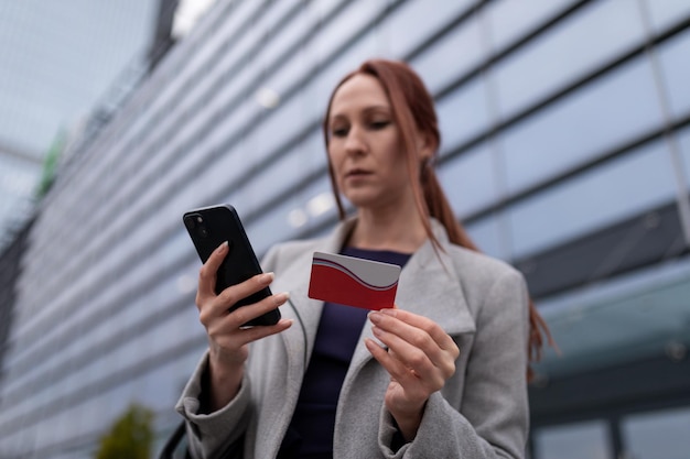 La donna di affari paga con carta online sullo sfondo di un edificio per uffici