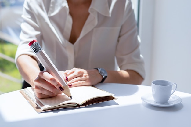 La donna di affari scrive in un taccuino con una grande matita.