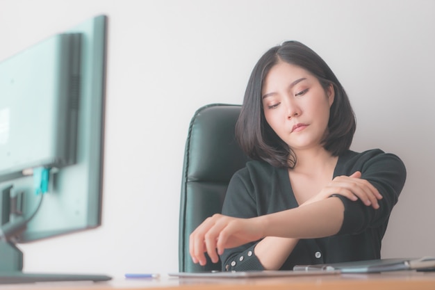 La donna di affari sta riposando e massaggiando la sua spalla nella sedia dell&#39;ufficio