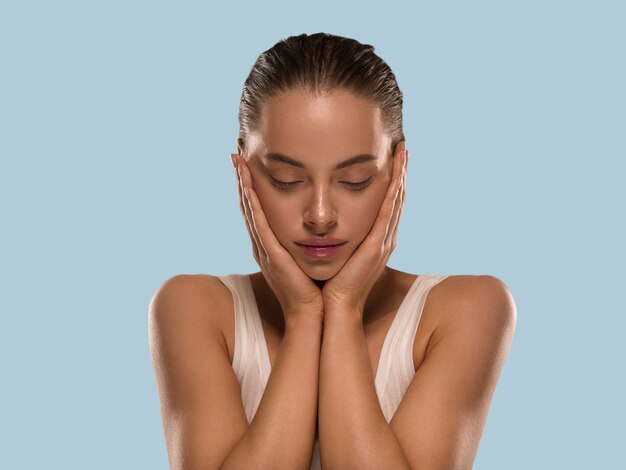 La donna di bellezza con le mani naturali sane compone il fondo di colore di concetto della pelle fresca pulita blu