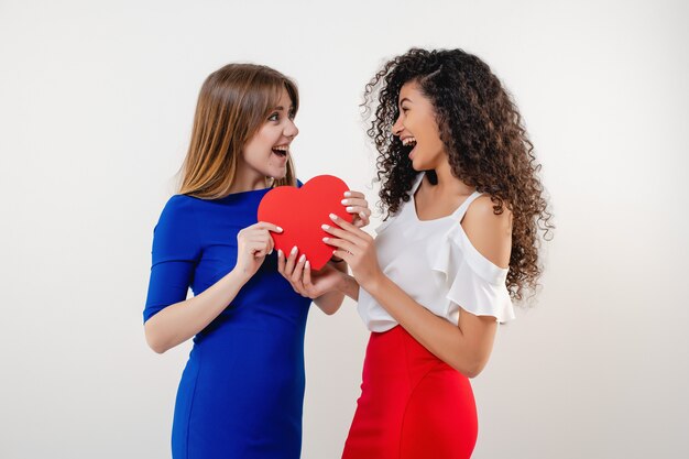 La donna di colore con l'amica che divide il cuore del biglietto di S. Valentino ha modellato la carta isolata