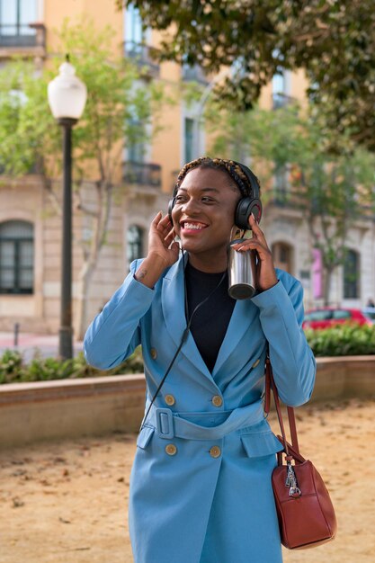 La donna di colore sta ascoltando musica con le cuffie in un parco di una città