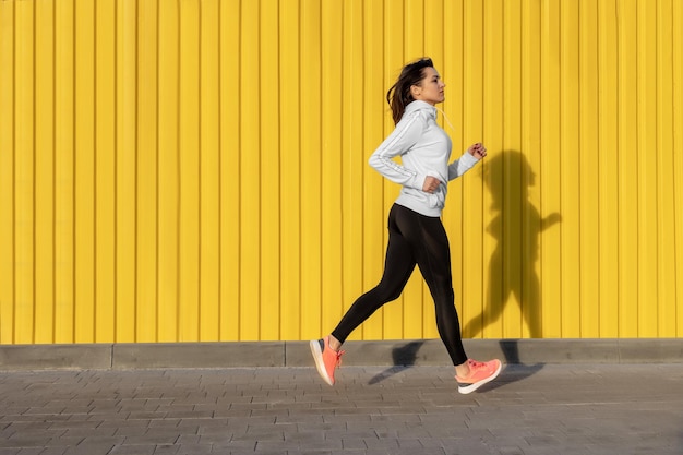 La donna di forma fisica sta funzionando all'aperto nell'ambiente urbano