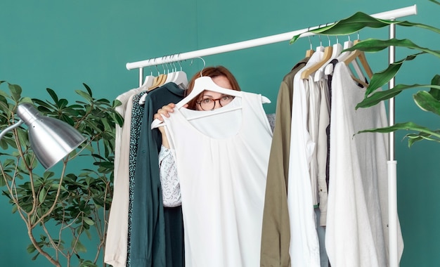 La donna di mezza età fa shopping e guarda il nuovo vestito vicino allo scaffale con i vestiti.