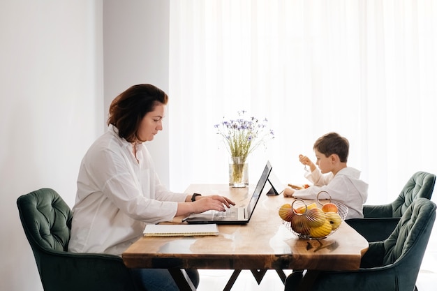 La donna di mezza età freelance sta lavorando su laptop e telefono