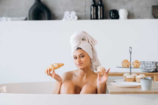 La donna di moda di lusso al mattino fa colazione sdraiata nella vasca da bagno