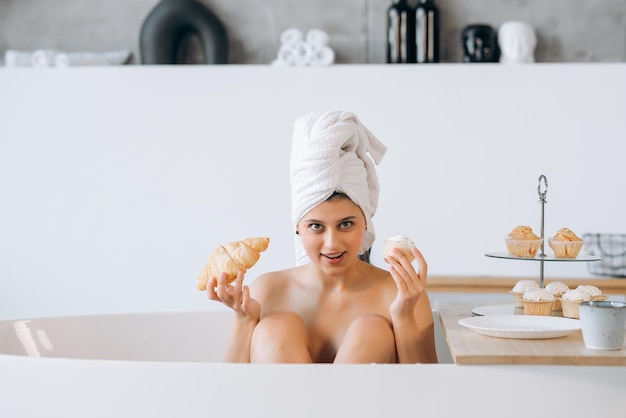 La donna di moda di lusso al mattino fa colazione sdraiata nella vasca da bagno