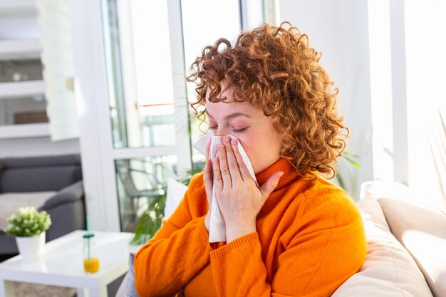 La donna disperata malata ha influenza. Rinite, raffreddore, malattia, concetto di allergia. La donna abbastanza malata ha il naso che cola, si strofina il naso con il fazzoletto. Starnuti femminile. Bruna starnuti in un fazzoletto