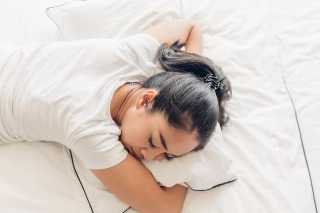 La donna dorme sul suo letto bianco nell'appartamento.