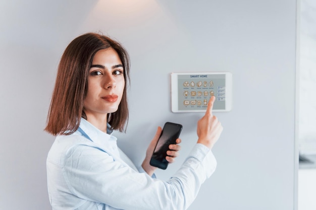 La donna è al chiuso controllando la tecnologia della casa intelligente