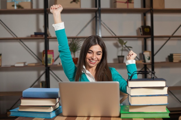 La donna è felice del suo lavoro di successo al tavolo di legno