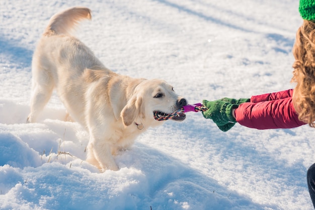 La donna e il suo cane golden retriever che giocano nella neve