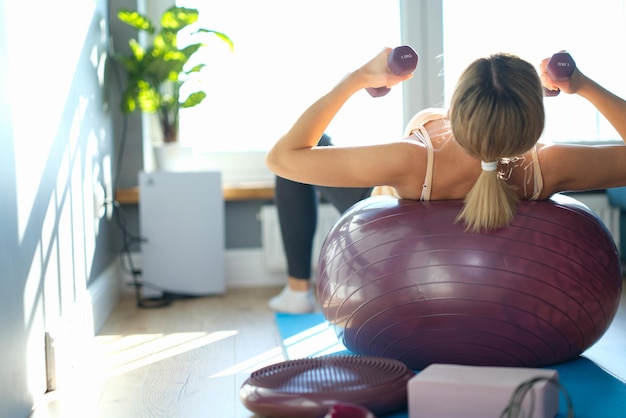 La donna è impegnata nel fitball e tiene i manubri