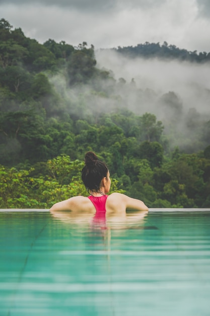 La donna e la piscina a guardare la scena di fronte alla foresta nebbiosa