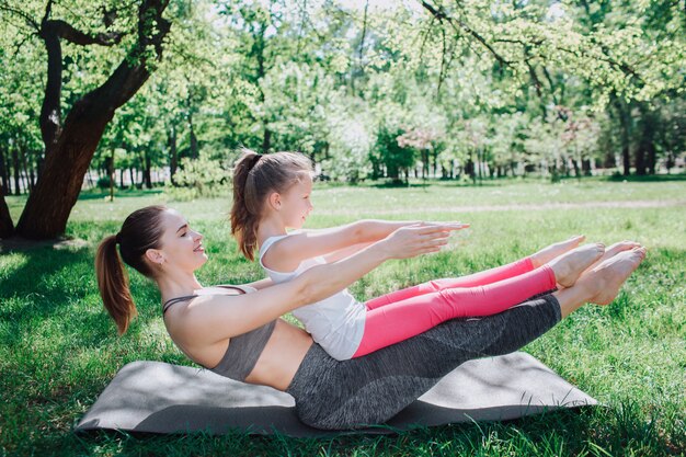 La donna e la ragazza stanno allungando sulla stuoia in parco