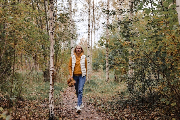 La donna è nel parco autunnale Passeggiata attraverso la foresta Atmosfera autunnale