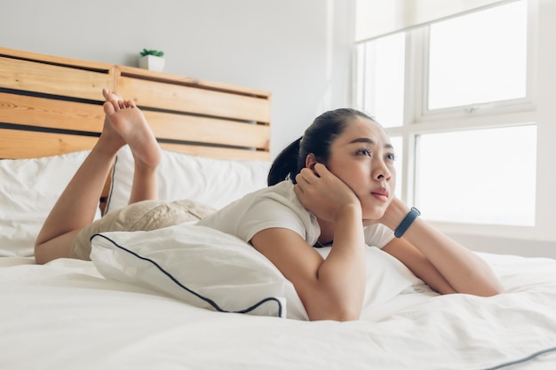 La donna è sdraiata sul letto e sta seriamente guardando una serie tv drammatica.