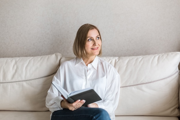 La donna è seduta con un libro in mano e sorride