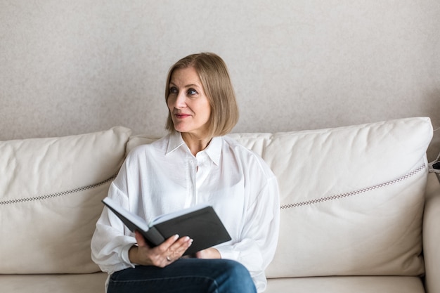 La donna è seduta con un libro in mano.