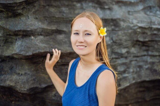 La donna è una turista a Bali. Il rituale dell'abluzione con l'acqua santa e sulla sua fronte prikleeli riso e mettere la spiga del fiore