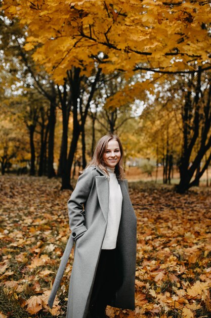 la donna entra lungo il vicolo autunnale del parco una ragazza con un cappotto grigio