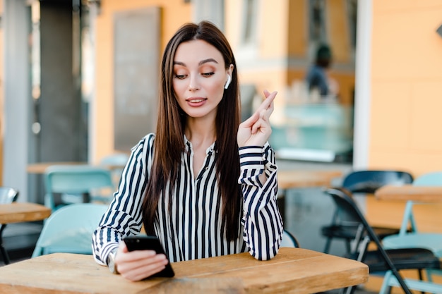 La donna esamina il telefono e tiene le dita incrociate sperando in fortuna