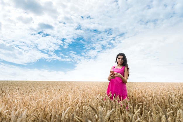 La donna esile felice sexy cammina di estate in un campo di grano. Signora che si gode il passatempo in campagna