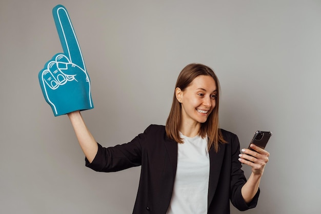 La donna estatica guarda la partita al telefono mentre indossa un guanto da dito in schiuma