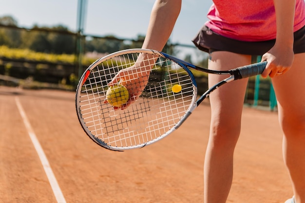 La donna europea caucasica tiene la palla verde gialla che gioca la partita di tennis sulla superficie del campo in terra battuta
