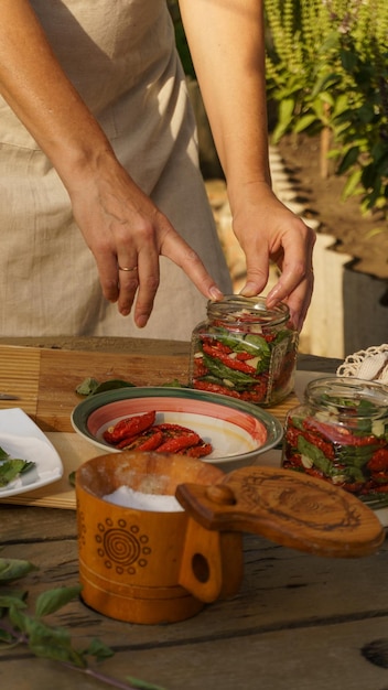 la donna fa i preparativi per l'inverno: pomodori secchi, aglio tritato e basilico fresco