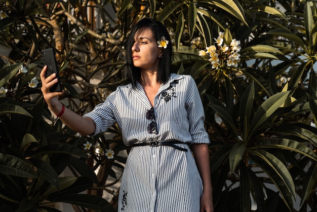 La donna fa il selfie in giardino con i fiori