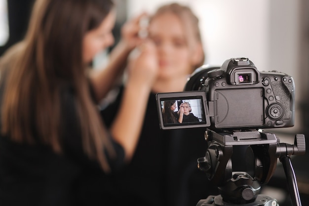 La donna fa il trucco per la donna attraente capelli biondi in studio.