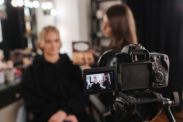 La donna fa il trucco per la donna attraente capelli biondi in studio.